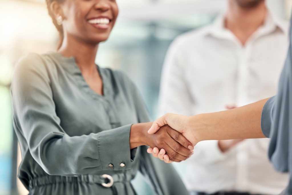 An INW account representative shaking hands with an independent convenience store owner in Oklahoma, representing a true wholesale partnership.
