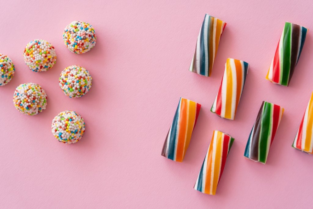 Flat lay with different colorful sweets on pink background