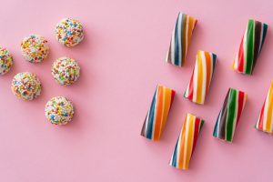 Flat lay with different colorful sweets on pink background